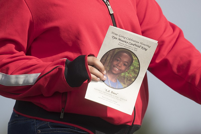 FILE - In this Sept. 24, 2016 file photo, a funeral service card bearing the likeness of Tyre King, the 13-year-old Ohio boy who was fatally shot by Columbus police, is carried by a mourner in Columbus, Ohio.  Columbus, Ohio, police officer Bryan Mason shot  King, after a suspected robbery last year feared a gunfight with the teen, who the officer said pulled a gun from his pants, records show.  Mason fired when he saw a laser sight on the gun, which turned out to be a BB gun, Mason said in a formal statement and interview with detectives obtained by The Associated Press through a records request.  (AP Photo/John Minchillo, File)