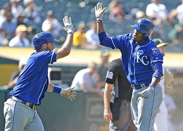 Royals teammates Alcides Escobar (right) and Drew Butera celebrate after Escobar scored during the ninth inning of Wednesday afternoon's game against the Athletics in Oakland, Calif.