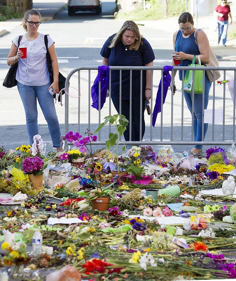 People visit a memorial at the site in Charlottesville, Va., on Friday, Aug. 18, 2017, where Heather Heyer was killed. Heyer was struck by a car while protesting a white nationalist rally on Saturday Aug. 12. (AP Photo/Cliff Owen)