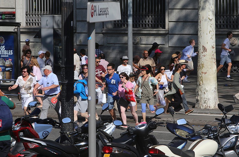 People flee the scene in Barcelona, Spain, Thursday, Aug. 17, 2017 after a white van jumped the sidewalk in the historic Las Ramblas district, crashing into a summer crowd of residents and tourists and injuring several people, police said.