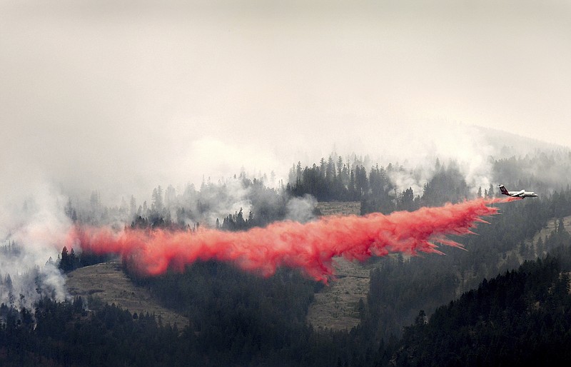 A bomber drops a load of fire retardant below the Lolo Peak fire creeping down the face of the ridge toward the Bitterroot Valley, Friday, Aug. 18, 2017 in Missoula, Mont. The Lolo Peak Fire in western Montana blew up overnight leading law enforcement officers to order the evacuation of up to 400 more homes west of the town of Lolo. (Kurt Wilson/The Missoulian via AP)
