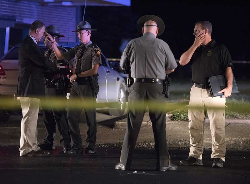 Law enforcement agents investigate the scene of a shooting on Friday, Aug. 18, 2017 in  Fairchance, Pa.  A Pennsylvania state trooper was critically injured when he was shot by a suspect in a robbery investigation before officers returned fire killing the shooter, state police said Saturday. A second trooper also was shot by the suspect Friday night outside a grocery store in Fairchance. The officer was treated at a hospital and released, authorities said. The suspect was identified as 26-year-old Clarence Belsar III.  (Haley Nelson/Pittsburgh Post-Gazette via AP)