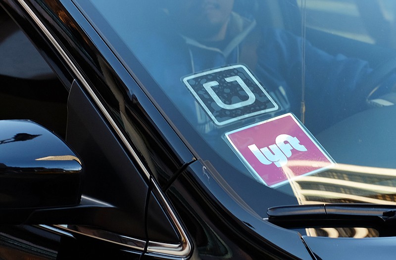 In this Tuesday, Jan. 12, 2016, file photo, a driver displaying Lyft and Uber stickers on his front windshield drops off a customer in downtown Los Angeles. Hailing a ride with a smartphone app in many U.S. cities could come down to a fight over fingerprints. Following incidents where Uber drivers were found to have criminal records, a growing number of state and local governments want ride-hailing drivers to undergo fingerprint background checks. Uber and its chief rival, Lyft, have fought those checks, contending their own method of vetting drivers is just as safe. 