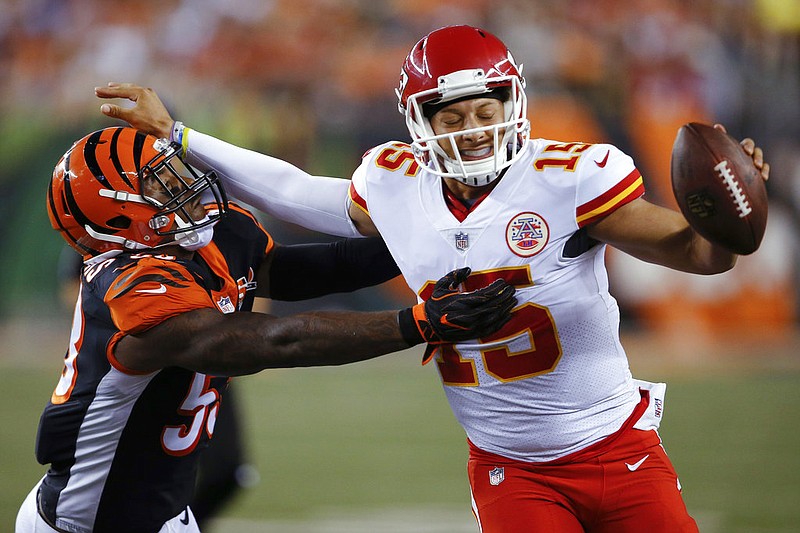 Kansas City Chiefs quarterback Patrick Mahomes (15) stiff-arms Cincinnati Bengals outside linebacker Marquis Flowers (53) during the second half of an NFL preseason football game, Saturday, Aug. 19, 2017, in Cincinnati. 