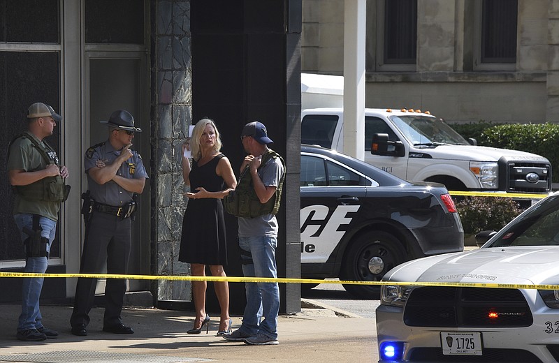 Officials consult near the crime scene at the Huntington Bank,  next to the Courthouse  in Steubenville, Ohio, Monday Aug. 21, 2017, after Jefferson County Judge Joseph Bruzzese Jr. was ambushed and shot while walking to work early Monday morning. (Darrell Sapp/Pittsburgh Post-Gazette via AP)