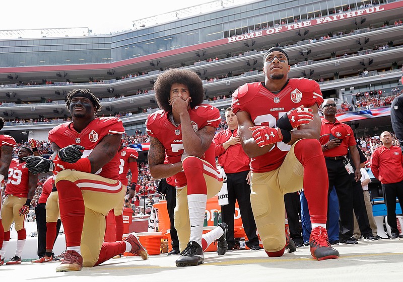 In this Oct. 2, 2016, file photo, from left, San Francisco 49ers outside linebacker Eli Harold, quarterback Colin Kaepernick, center, and safety Eric Reid kneel during the national anthem before an NFL football game against the Dallas Cowboys in Santa Clara, Calif. What started as a protest against police brutality has mushroomed a year later into a divisive debate over the future of Kaepernick who refused to stand for the national anthem and now faces what his fans see as blackballing for speaking out in a country roiled by racial strife. The once-rising star and Super Bowl quarterback has been unemployed since March, when he opted out of his contract and became a free agent who could sign with any team.