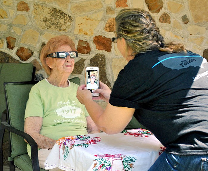 Deb Taylor takes a picture of her grandmother Hildegarde Haslag with her total eclipse glasses on during Haslag's 100th birthday celebration Monday at her Loose Creek home. 