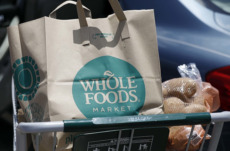 FILE - In this Friday, June 16, 2017, file photo, groceries from Whole Foods Market sit in a cart before being loaded into a car, outside a store in Jackson, Miss. On Wednesday, Aug. 23, 2017, Whole Foods shareholders will be voting on whether to approve Amazon’s $13.7 billion takeover bid of the organic grocer. (AP Photo/Rogelio V. Solis, File)