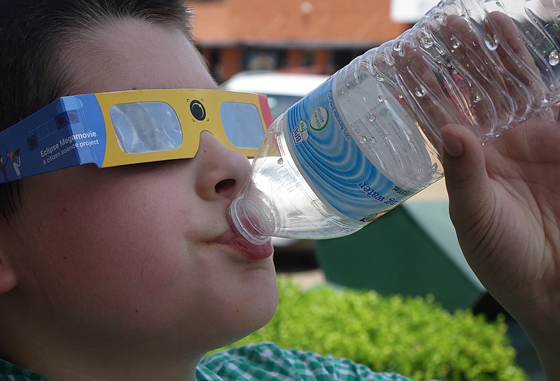 Ethan Strutton, 10, takes a drink of water during the eclipse Monday in Atlanta, Texas. He attended a party at the public library.
