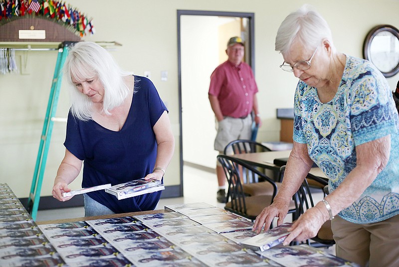 Kay Jarboe, left, and Carolyn Scheperle organize DVDs of "The Patriot" on Tuesday in the conference room at Hy-Vee. The movies were set out during an Operation Bugle Boy meeting organizing the Patriot Sunday dinner in September.