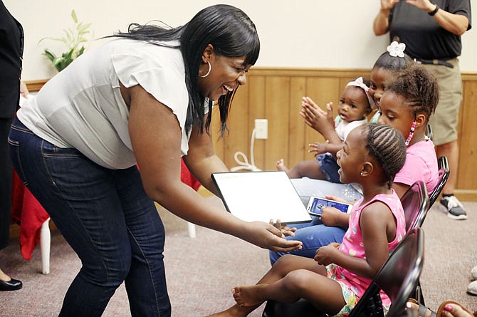 Kwajalyn Galtney, left, is congratulated Thursday by her niece, Kaylin Hayslett, 3, during the Family Self-Sufficiency Program graduation at Jefferson Plaza. The FSS program helps participants to become homeowners through a five-year educational program.