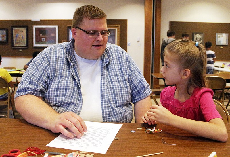 Emil Lippe/News Tribune 
Brian Mueller and his daughter Avery, 7, go over the steps to making their own fidgit spinner from cardboard and pennies during the Maker Day with LabSpace Robotics at the Missouri River Regional Library on Saturday, August 26, 2017. Participants used hot glue to secure the pennies onto their own cut out fidgit spinners.