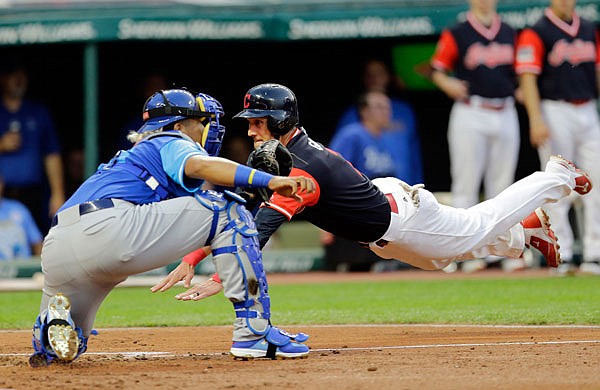 Yan Gomes of the Indians dives into home as Royals catcher Salvador Perez waits for the ball in the third inning of Friday night's game in Cleveland.