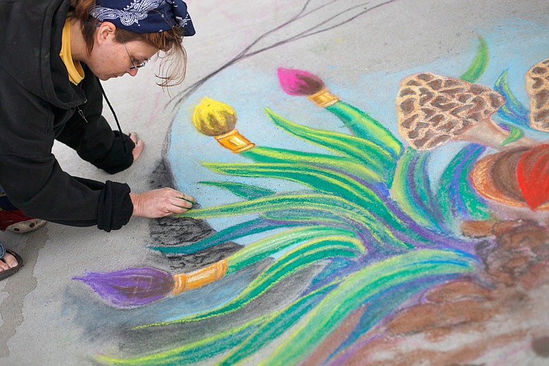 Despite the rain, Jennifer Neff continue to work on her chalk art piece at the 2014 fair at Warwick Village in Jefferson City.