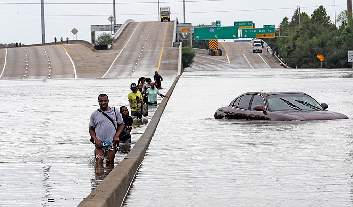 Evacuees wade down a flooded section of Interstate 610 as floodwaters from Tropical Storm Harvey rise Sunday in Houston. The remnants of Hurricane Harvey sent devastating floods pouring into Houston as rising water chased thousands of people to rooftops or higher ground.