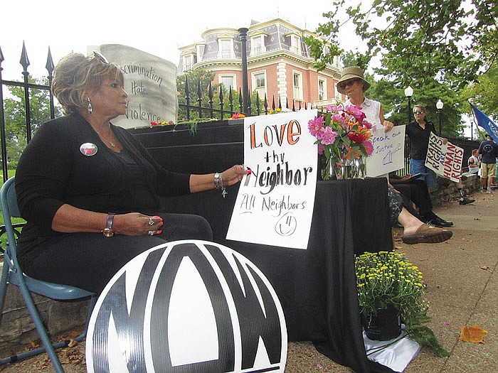 Freeda McKee, vice president of Capital Area Missouri chapter of the National Organization for Women, holds a sign at Sunday's rally at the Governor's Mansion. The NAACP described the rally as mourning for the loss of civil rights in Missouri, including a bill taking effect today that makes it harder to win a discrimination lawsuit. Behind her is a mock casket with the words "discrimination," "hate" and "violence."