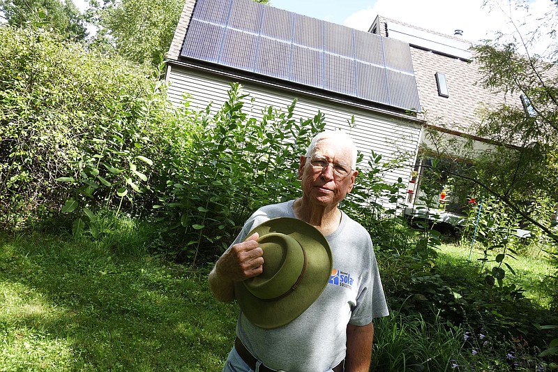 Millersburg-area homeowner Leemer Cernohlavek stands next to a butterfly garden on the south side of his home. The 14 large solar panels, installed just five years ago, feed electricity into the "grid," offsetting his electric bill, and the smaller solar panels to the right operate his hot water tank.