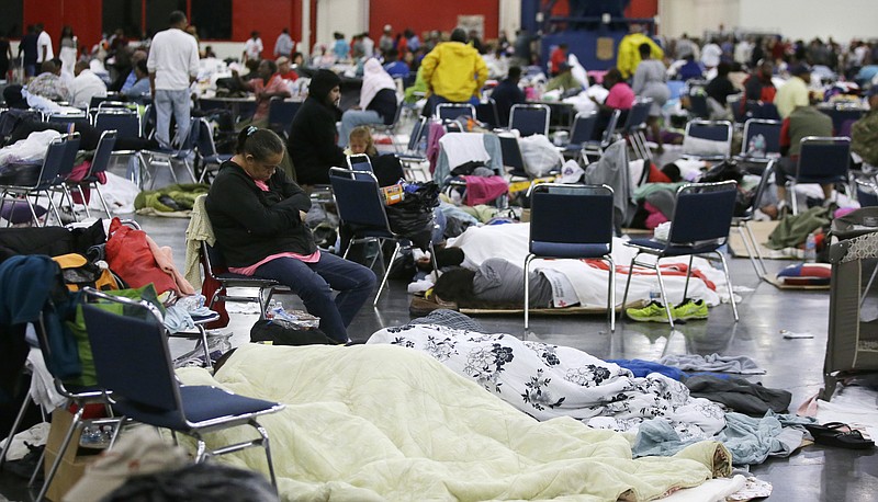 People rest at the George R. Brown Convention Center that has been set up as a shelter for evacuees escaping the floodwaters from Tropical Storm Harvey in Houston on Tuesday, Aug. 29, 2017. (AP Photo/LM Otero)