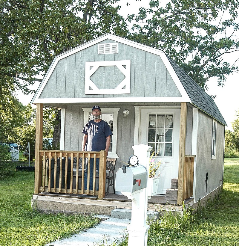 In this August 2017 photo, Michael Garrison stands on the porch of his "tiny house" in California. The 200-square-foot home is compact, but with the necessities, including kitchen and bathroom facilities.