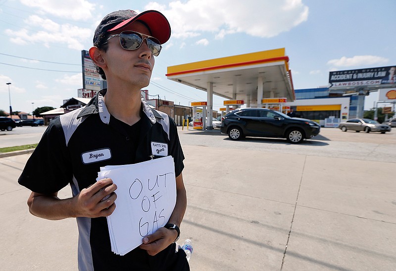 Employee Bryan Herrera holds a makeshift sign that reads, "Out of Gas," as he stands outside the Shell filling station where he works, in north Dallas, Thursday, Aug. 31, 2017. It's getting harder to fill gas tanks in parts of Texas where some stations are out of fuel and pump costs are spiking. A major gasoline pipeline shuttered due to Harvey may be able to resume shipping fuel from the Houston area by Sunday, which could ease gasoline shortages across the southern U.S. 