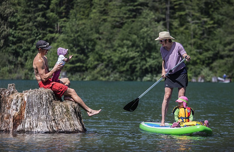 Margaret Wheeler paddleboards on Rattlesnake Lake near North Bend with a passenger onboard -- her 2-year-old daughter -- while getting the attention of her 7-month-old daughter, being held by her husband, Matt Farmer. Wheeler says the addition of baby No. 2 has added logistical challenges to the couple's guiding routine. "It's not double (the work)," she says. "It's five times. I underestimated how much of my mental bandwidth would be taken up by having a second."