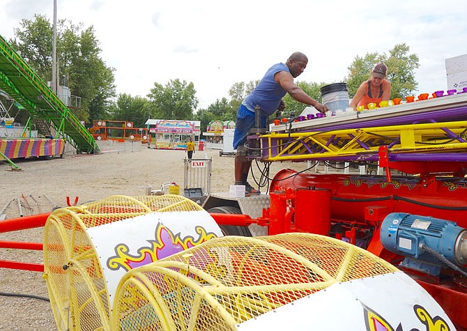 Mary Bass, right, and Strauss, of Fountain City Amusements, swap out lights on a carnival ride Thursday, Aug. 31, 2017 in Mokane in advance of the Mokane Lions Club Fall Festival. 