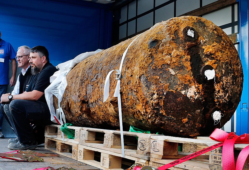 Disposers Dieter Schwaetzler, left, and Rene Bennert sit next to 1.8 ton WWII bomb right after they defused it, in Frankfurt, Germany, Sunday, Sept. 3, 2017. 70 000 people had to be evacuated.  Police say bomb disposal experts have successfully defused a huge World War II-era bomb in the German financial capital Frankfurt that forced the evacuation of more than 60,000 residents. 