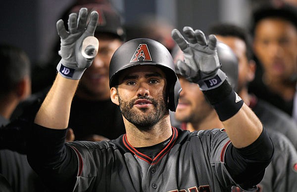 J.D. Martinez of the Diamondbacks gestures toward the camera as he walks in the dugout after hitting his fourth home run of the game in the ninth inning Monday night against the Dodgers in Los Angeles.