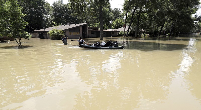 Gaston Kirby, right, and Juan Minutella leave Kirby's flooded home in the aftermath of Hurricane Harvey, Monday, Sept. 4, 2017, near the Addicks and Barker Reservoirs, in Houston. (AP Photo/David J. Phillip)