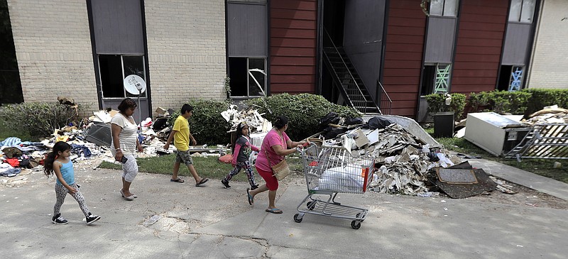 A family walks past debris from a flooded apartment complex in the aftermath of Hurricane Harvey Tuesday, Sept. 5, 2017, in Houston. (AP Photo/David J. Phillip)