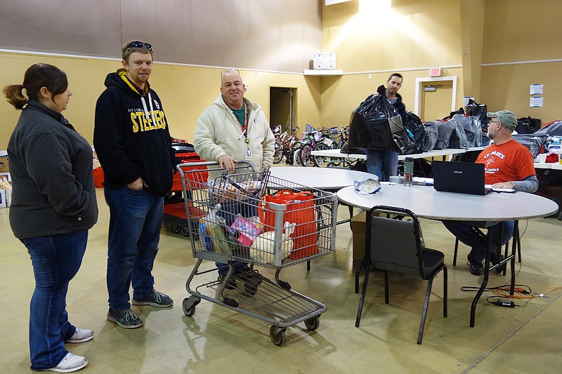 Volunteers and Adopt-A-Family participants take part in the loading system in 2016. Gifts wait to be distributed in the background.