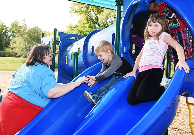 Sandy Barnes, who works at Scholastic, went to CMCA's Head Start preschool near Lincoln University to help with the 4- and 5-year-old students as part of the United Way's Days of Caring program. Here, she encourages Caiden Dennis to go down the slide while Jada Humphrey prepares to slide on her knees.