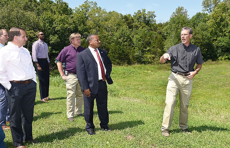City Engineer David Bange, at right, talks about the stormwater basin behind him and how it controls the flow of excess water in heavy rains. In early September, several members of the Jefferson City Council joined city Public Works staffers on a bus tour of stormwater trouble spots in town.