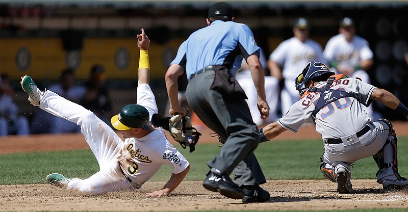 Oakland Athletics' Boog Powell, left, slides to score past the tag of Houston Astros catcher Juan Centeno in the second inning of the first baseball game of a doubleheader on Saturday, Sept. 9, 2017, in Oakland, Calif. Powell scored on an error by Astros' pitcher Charlie Morton. 