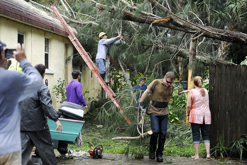 Steve Miccio secures a tree limb with a rope as he and others work to remove the tree from the roof of his Gulf Road home Tarpon Springs, Fla., Monday, Sept. 11, 2017. Miccio and his family were not home at the time when the tree fell. Hurricane Irma brought heavy wind and rain as it passed Tampa Bay. (Chris Urso/Tampa Bay Times via AP)