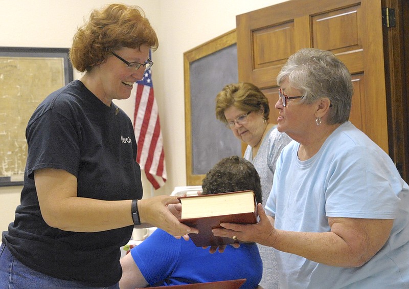 Marcia Davis, lead investigator with the Midwest Ghost Hunters, accepted the gift of a Moniteau County Missouri History book from Leah McNay, vice president of the Moniteau County Historical Society, on Sept. 11 2017, following Davis' presentation on discoveries made by her team inside the society's museum last fall.