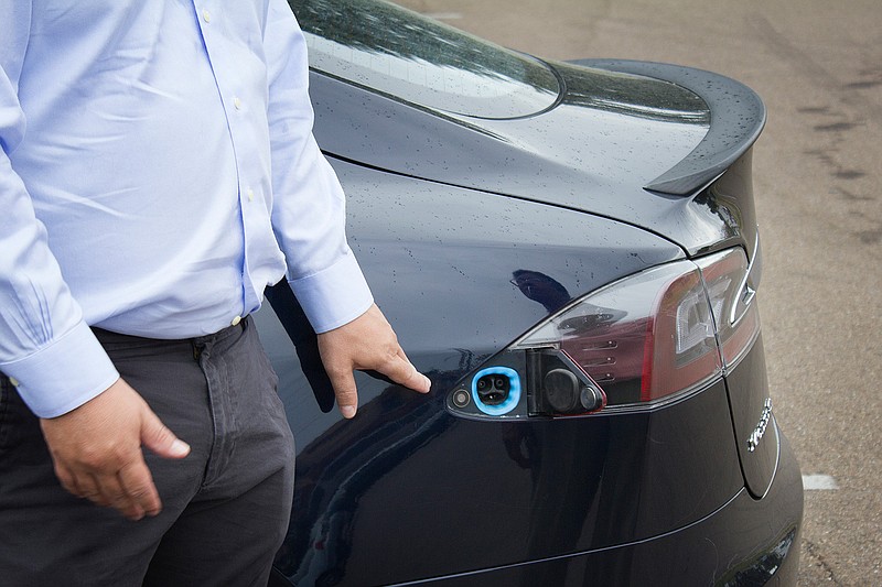 Luis Castilla, press officer for nonprofit advocacy group Public Citizen, demonstrates the charging port for a Tesla electric automobile Tuesday at a Friends United for a Safe Environment meeting in Texarkana. He is driving the car on a multicity tour through Texas to raise awareness of climate change and global warming.
