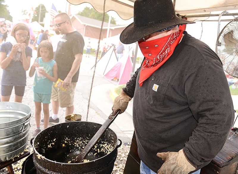 Alan Finke shields his face with a bandana during last year's Oktoberfest as he stirs a piping hot batch of kettle corn for customers. Finke's kettle was passed down by his grandmother and has been used by his family for generations. Now, it's sole purpose is for making kettle corn.