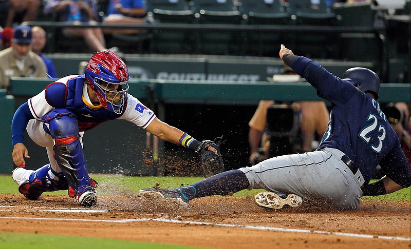 Texas Rangers catcher Robinson Chirinos tries to tag Seattle Mariners' Nelson Cruz (23), who scored during the second inning of a baseball game, Tuesday, Sept. 12, 2017, in Arlington, Texas. 