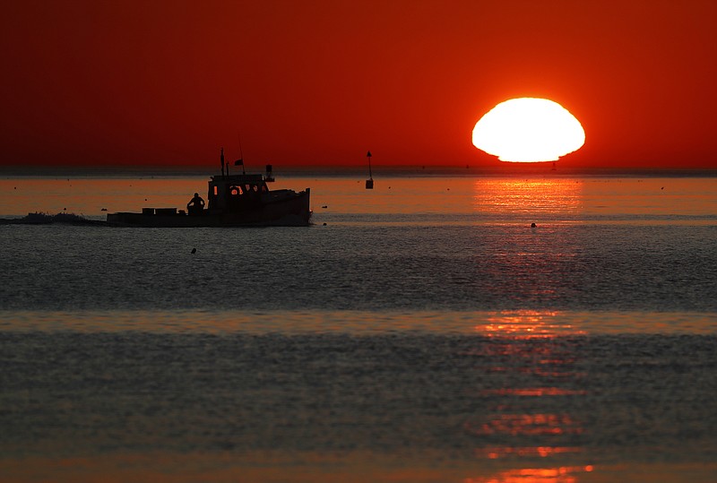 In this Wednesday, Sept. 13, 2017, photo, a lobster fishing boat heads out to sea at sunrise off Portland, Maine. Scientists say the Gulf of Maine, which stretches from Massachusetts to Nova Scotia, is warming faster than almost all of Earth's waters. (AP Photo/Robert F. Bukaty)