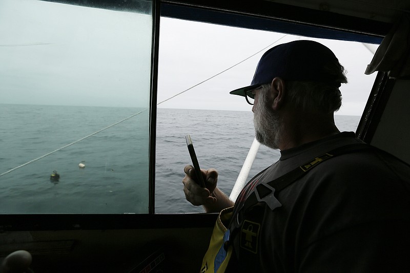 In this Monday, Aug. 7, 2017 photo, Jake Bunch uses his phone to mark the position of an abandoned crab pot off Half Moon Bay, Calif. Fisherman like Bunch are using GPS positioning in their cellphones to voluntarily step up recovery of abandoned crab pots before they snare whales. Some environmental groups say the state should put in place more mandatory protection measures, such as blocking fishermen from especially important waters for whales. (AP Photo/Eric Risberg)