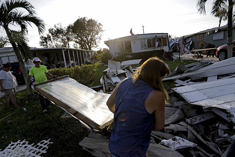 Joseph Ross, left, cleans up debris from his damaged home with help from a neighbor in the aftermath of Hurricane Irma in Naples, Fla., Wednesday, Sept. 13, 2017. (AP Photo/David Goldman)