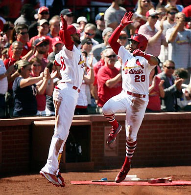 Tommy Pham (28) high-fives Cardinals teammate Jose Martinez as he returns to the dugout after hitting a two-run home run in the fifth inning of Thursday afternoon's game against the Reds at Busch Stadium.