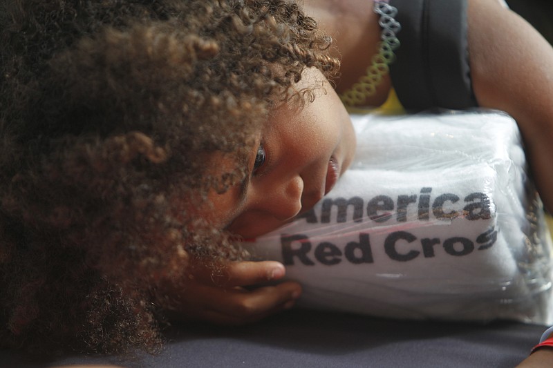 A girl rests her head on a set of towels supplied by the American Red Cross at a makeshift shelter, after arriving in San Juan, Puerto Rico, Thursday, Sept. 14, 2017, on a cruise ship with families evacuated from Caribbean islands devastated by Hurricane Irma. Puerto Rico transformed their largest convention center into a shelter for some of the hurricane victims. Some of those arriving via the cruise ship said they would stay with friends and family in the U.S. mainland until they got a better idea on how long reconstruction would take. 