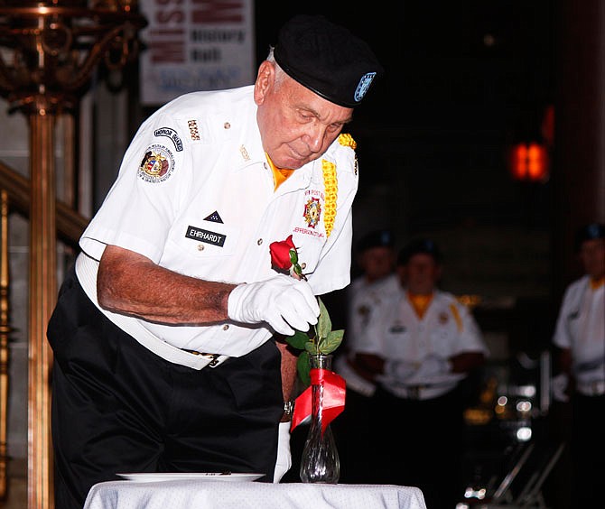 Missouri Honor Guard member Art Ehrhardt places a rose in a vase, symbolizing soldiers who were either taken as prisoners of war or who had gone missing in action during a POW/MIA Recognition Day on Friday at the Capitol. 