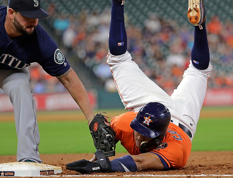 Houston Astros' Carlos Correa, right, is tagged out by Seattle Mariners first baseman Yonder Alonso on a pickoff play during the third inning of a baseball game Friday, Sept. 15, 2017, in Houston.