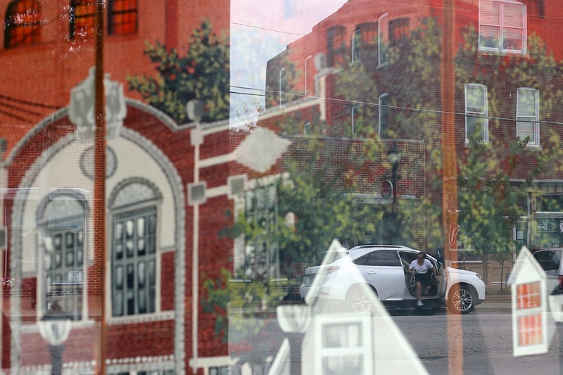 A woman gets out of her car in the reflection of a mural on East Dunklin Street on July 22, 2015. The mural "commemorates the role of the South Side in Jefferson City history. Settled by German immigrants around the time of the Civil War and known as Muenchberg or Munichburg, the South Side became its own distinct residential and business community by the turn of the twentieth century," according to a description on the mural.