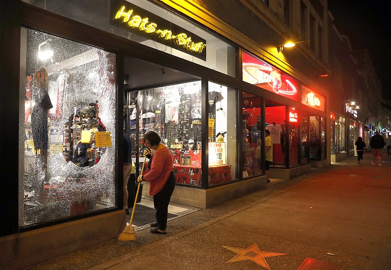 FILE - In this Sept. 17, 2017 file photo, Lori Shifter helps clean up after a violent crowd broke windows in University City, Mo. When a former police officer was acquitted in the fatal shooting of a black suspect, protesters vowed to show their disdain by disrupting business in downtown St. Louis. (AP Photo/Jeff Roberson, File)