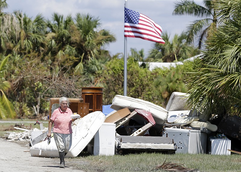 <p>AP</p><p>A woman walks by a pile of debris caused by storm surge during Hurricane Irma in Everglades City, Florida. The isolated community of about 400 people suffered some of Florida’s worst storm surges.</p>