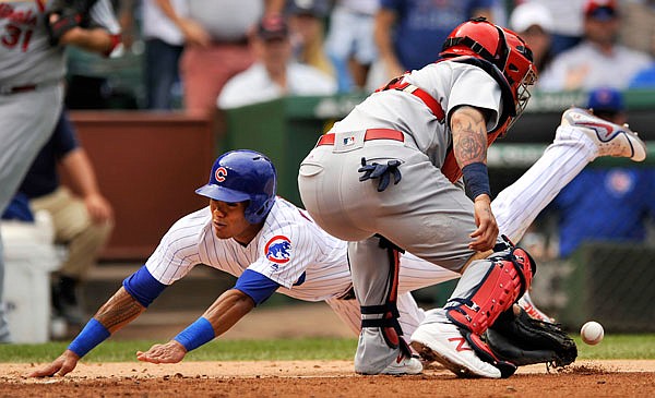 Addison Russell of the Cubs slides safely into home on a Ben Zobrist single as Cardinals catcher Yadier Molina bobbles the throw during the fourth inning of Sunday afternoon's game in Chicago.